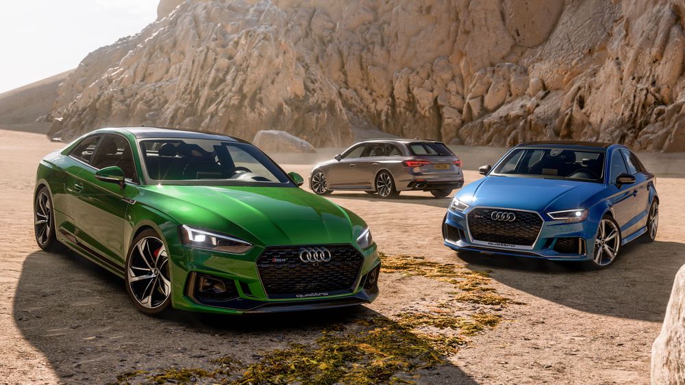 Three Audi cars of different colors posed together in a rocky landscape.