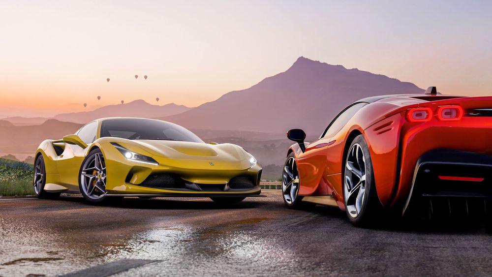 Two Ferrari cars posed together in front of a mountain in the distance.