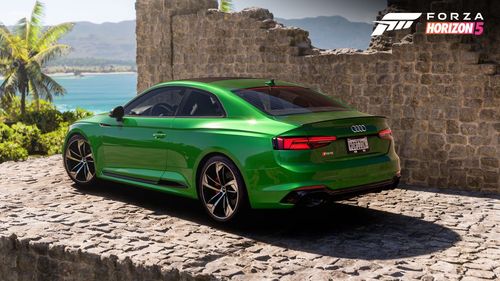 Green audi posed among Mexican ruins with the ocean in the background.