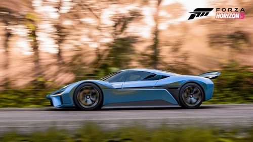 A side view of the blue NIO EP9 as it drives at speed on a road in a forest as sun rays shine through the trees.