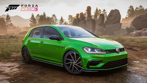 A green Volkswagen Golf R parked in the canyon by rocky structures.