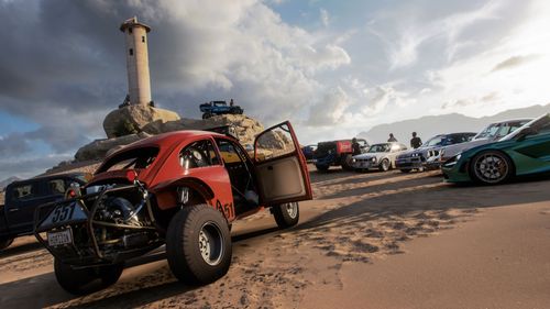 A Convoy of drivers park up their vehicles on a beach by a lighthouse. There's a red buggy and a green supercar amongst the collection.
